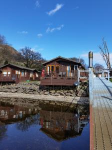 a house next to a body of water at Bonnie Banks Lodge Ardlui in Ardlui