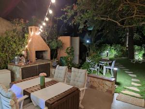 eine Terrasse mit einem Tisch, Stühlen und einem Kamin in der Unterkunft Emerald Cottage Calaverde Santa Margherita di Pula in Fort Village