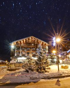 un lodge avec un arbre de Noël dans la neige la nuit dans l'établissement Hôtel Le Refuge, à Tignes