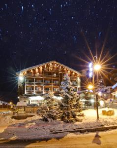 eine Lodge mit einem Weihnachtsbaum im Schnee in der Nacht in der Unterkunft Hôtel Le Refuge in Tignes