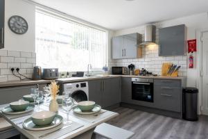 a kitchen with a table with bowls on it at Air Host and Stay - Conningsby House - Beautiful 6 bedroom sleeps 14 minutes to LFC in Liverpool