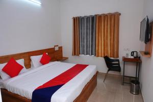 a bedroom with a large bed with red and blue pillows at Hotel Stay Shine in Mysore