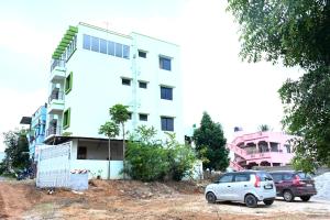a white building with two cars parked in front of it at Hotel Stay Shine in Mysore