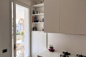 uma cozinha com armários brancos, uma mesa e uma janela em San Martino Apartment - Moniga del Garda em Moniga