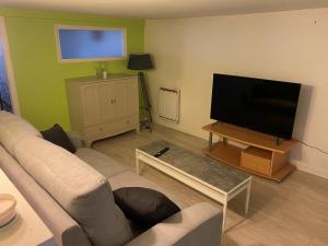 een woonkamer met een bank en een flatscreen-tv bij Proximité Biarritz - Arcangues in Arcangues