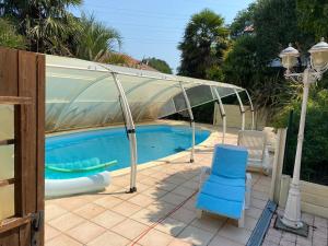 a swimming pool with a canopy and a blue chair at Proximité Biarritz - Arcangues in Arcangues