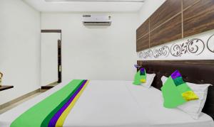 1 dormitorio con 1 cama blanca grande con almohadas coloridas en Itsy By Treebo - Anjali Mahal 500 Mtrs From Mathura Railway Station en Mathura