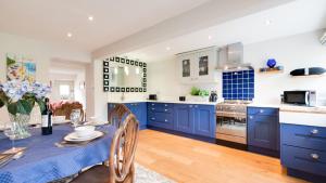 eine Küche mit blauen Schränken und einem Tisch mit Stühlen in der Unterkunft Bobbin Cottage in Belper