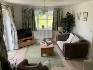 a living room with a couch and a tv at Cosy country cottage with outdoor bathing in Halkyn