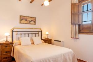 um quarto com uma cama branca, 2 candeeiros e uma janela em Cortijo La Presa em Priego de Córdoba