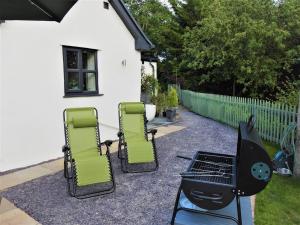 a group of chairs and a grill in a yard at Cosy country cottage with outdoor bathing in Halkyn