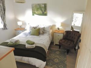 a small bedroom with a bed and a chair at Cosy country cottage with outdoor bathing in Halkyn