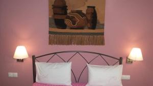 een bed met twee witte kussens en een schilderij aan de muur bij House Roula in Neos Marmaras