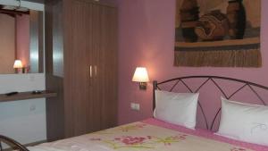 um quarto com uma cama com paredes cor-de-rosa em House Roula em Neos Marmaras