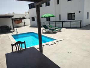 una piscina con mesa, sillas y sombrilla en Finca La Tabaiba Apartamento alto, en Máguez