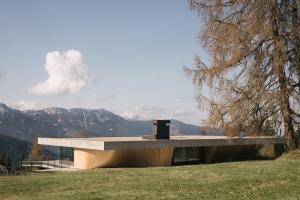 a building on a hill with mountains in the background at anders mountain suites 2 in Brixen