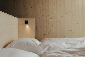 a bedroom with two white beds and a wooden wall at anders mountain suites 6 in Brixen