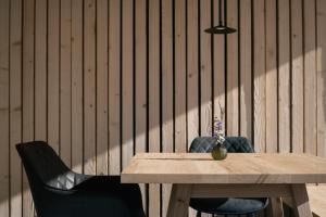 a wooden table with two chairs and a vase with flowers at anders mountain suites 6 in Brixen