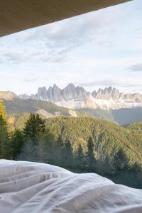 a bedroom with a view of mountains and trees at anders mountain suites 6 in Brixen