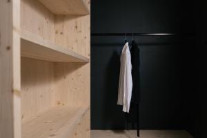 a closet with a black wall and a white coat on a rack at anders mountain suites 6 in Brixen