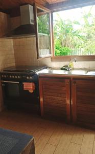 a kitchen with a stove and a sink and a window at La Caz'Anna in Cilaos