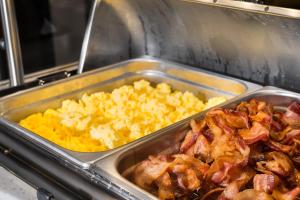 a tray of food with bacon and scrambled eggs at Holiday Inn Express and Suites Atlanta-Johns Creek, an IHG Hotel in Johns Creek