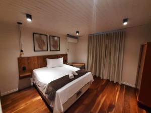 a bedroom with a large white bed and wooden floors at Pousada Somenzi in Bento Gonçalves