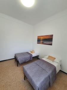 een kamer met 2 bedden en een schilderij aan de muur bij La casa della stazione in La Spezia