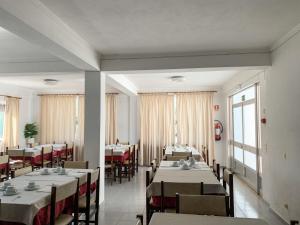 a dining room with tables and chairs and windows at Hotel Mateus in Fátima