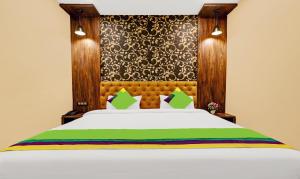 a bedroom with a white bed with a wooden headboard at Treebo Spring Brook in Guwahati