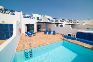 a swimming pool with blue chairs and a house at Coloradas Villa Alba in Playa Blanca