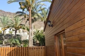 uma casa de madeira com uma cerca e palmeiras em Villas de Taurito em Taurito