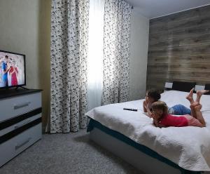 um homem e uma menina deitados numa cama em La Banel Hotel em Selemet
