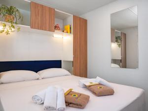 a bedroom with a white bed with towels on it at Club del Sole Rimini Family Resort in Rimini