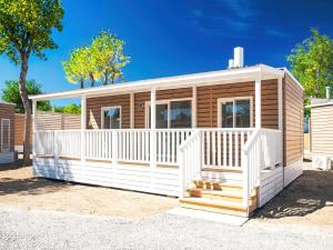 a wooden cabin with a white railing and a porch at Club del Sole Rimini Family Resort in Rimini