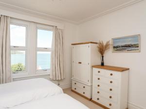 a bedroom with a bed and a dresser and windows at Bryn Ogwen in Bangor