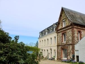 uma antiga casa de pedra e um edifício branco em Dans maison de charme, bel appartement privatif em Saint-Laurent-de-Brévedent