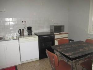 - une cuisine avec une table et une cuisinière noire dans l'établissement Le Perthuis, à Charnay-lès-Mâcon