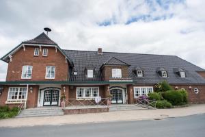 una gran casa de ladrillo rojo con techo negro en Landhaus Hamester - Hotel & Restaurant - neu eröffnet September 2022, en Basthorst