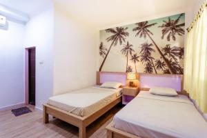 two beds in a room with palm trees on the wall at Segara Sadhu Inn Kuta by ecommerceloka in Kuta