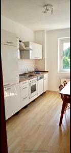 een keuken met witte apparatuur en een houten vloer bij Apartment Living Leipzig in Großzössen