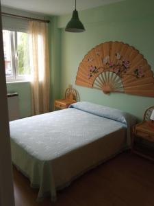 - une chambre avec un grand lit et une tête de lit en bois dans l'établissement APARTAMENTOS RAMÓN, à Foz