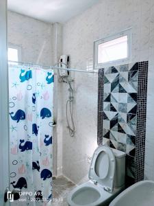 a bathroom with a shower curtain with a toilet at บ้านวาริ สะแกกรัง in Uthai Thani