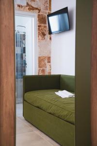 a green couch in a room with a tv on a wall at Olea Relais in Conversano