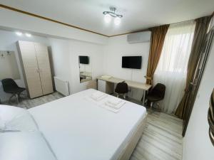 a room with a bed and a desk and a television at Hotel Marina srl in Bucharest