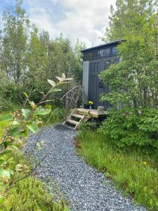 a tiny house in the woods with a gravel path at Valhalla Yurts Odin in Selfoss