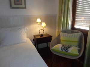 a bedroom with a bed and a chair and a lamp at Ténis Mar F in Albufeira