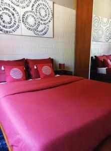a bedroom with a large pink bed with red pillows at La Caz'Anna in Cilaos