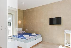 a bedroom with a bed and a tv on a wall at White Forest in Juodkrantė