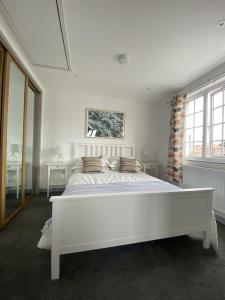 um quarto branco com uma grande cama branca com almofadas em The Crows Nest - Sheringham em Sheringham